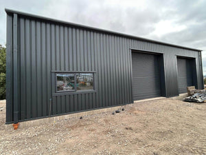 Dark grey steel building in Plymouth with two roller shutter doors and a side window
