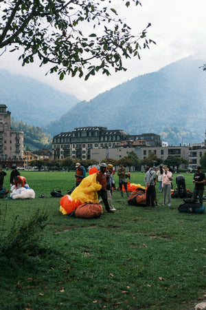 People preparing paragliders on a grassy field