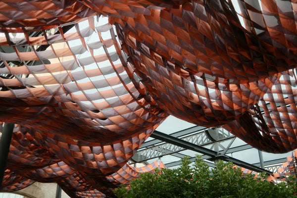 Abstract copper-colored ceiling structure with diamond patterns and green foliage