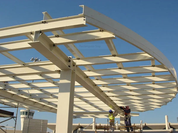 Two construction workers build a large white steel canopy structure.